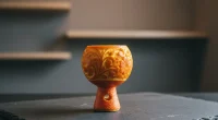 Крупный план фрукта, вырезанного под чашу для кальяна, лежащего на тёмной поверхности с мягким светом.