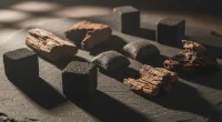 Различные типы угля для кальяна: кубики кокосового и куски древесного на темном фоне