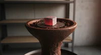 Крупный план кальянной чаши с табаком и тлеющим углем, в мягком свете