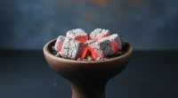 Крупный план кальянной чаши с неравномерно горящими углями и большим количеством пепла