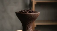 Крупный план тёмной глиняной чаши для кальяна с табаком под драматичным освещением