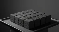 Несколько неразожженных кальянных углей на темном металлическом подносе