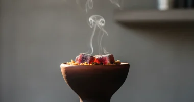 Макрофотография кальянной чаши с тлеющими углями, видны табак и лёгкий дым. Фокус на взаимодействии тепла и материала.