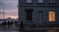 Вечерняя улица в Ульяновске, на фасаде здания замаскирована вывеска вейп-шопа, прохожие.